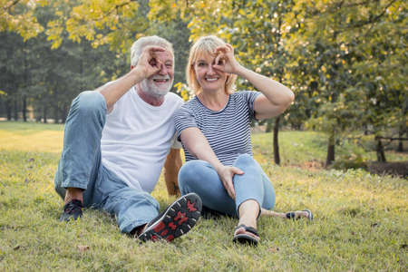 Senior couple sitting on the lawn in the park. Happy smiling of senior couple in a park on a holiday.の写真素材