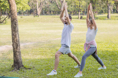 Young couples playing yoga in the park. Couples are exercising in the park.