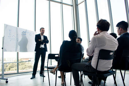 Chief explained that information on a whiteboard for employees to get to know and understand the work. Employees attending the chiefs described the information relating to the company.の写真素材