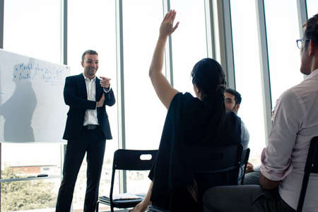 Employees raise their hands to inquire about the work in the company. Chief answers questions to those are suspected in the meeting.の写真素材