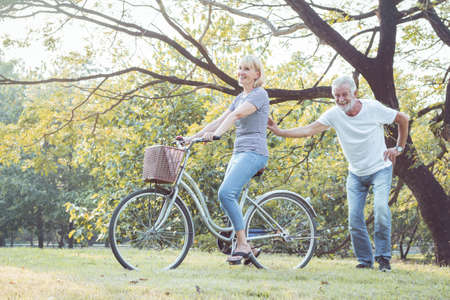 Couples elderly are bicycling together in the park. Couples elder play a bike together happily and fun. Concept of couples elderly good healthy and strong.の写真素材