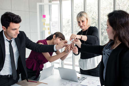Business synergies by holding a jigsaw together to demonstrate the sincerity of team. These business people holding jigsaw sincere together as a team. Closeup of businesspeople holding jigsaw puzzle.の写真素材