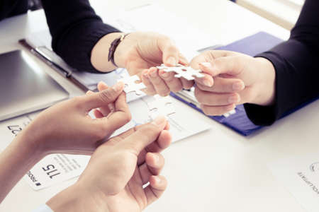 Hand holding the puzzles for the businessmen to work together as a team. Concept of planning work as...