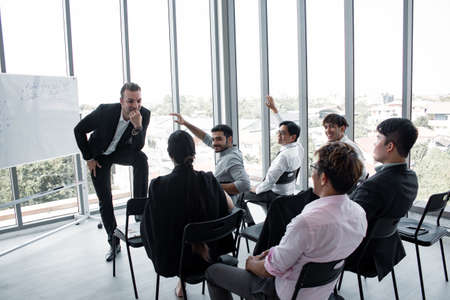 Chief listens comment to the staff in the team at the meeting. Staff expressed their opinions to the chief at the meeting room.  Employees raise their hands to ask leaders.の写真素材