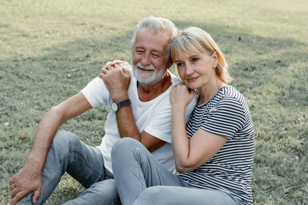 Senior couples sitting hug each other and smile happily in the park. Concept of an elderly lover.の写真素材