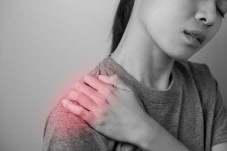 Woman with shoulder pain. Young woman with pain in shoulder. Suffering from pain in shoulder of woman.の写真素材
