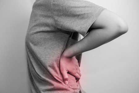 Woman with pain in the waist. Woman suffering from backache. Suffering from sudden back pain.の写真素材