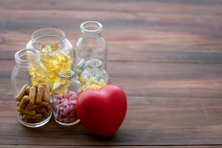 Medicine in bottle and heart on wood background. Concept of medicine in medical.の写真素材