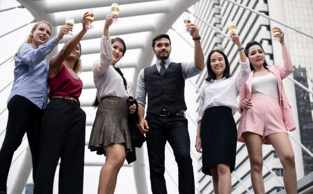 Business people clink glasses and drink wine to celebrate the successful work. Group of business people celebrate by drinking wine with smile.の写真素材