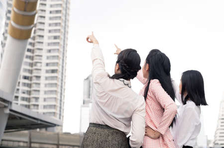 Group of asian business woman pointing forward with a smile in the concept of work progress at outdoor with background city. Thai women office worker group.の写真素材
