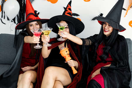 Gang of witch teen Thai women with celebrate Halloween party with smile in the room at home. Concept of party Halloween at home. Group young Asian women in costume witch celebrate in Halloween day.の写真素材