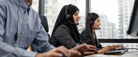 Panoramic of muslim woman and group of diverse telemarketing customer service staff team in call center. Call center worker accompanied by team. Smiling of customer support operator at work.の写真素材