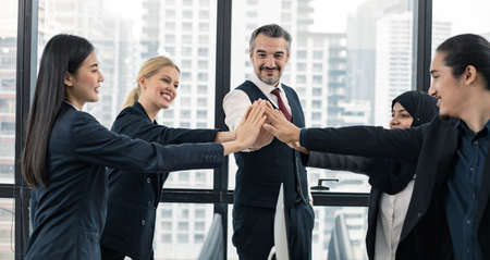 Teamwork successful business concept, leaders and office staff join hand together in succeed as team of small company in meeting room with happy smile and modern city background.の写真素材