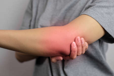 Women with pain in elbow. Acute pain in a elbow. Young woman holds on to elbow.の写真素材
