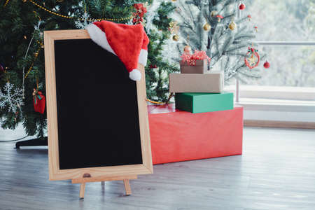 Copy space of blackboard for putting text and a red Santa Claus hat, decorated with Christmas themes in the room at home. Small board in Christmas festival. Merry Christmas and happy New Year concept.の写真素材