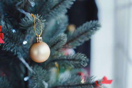 Closeup of gold ball hanging from a decorated Christmas tree with copy space. Christmas and New year holidays background.の写真素材