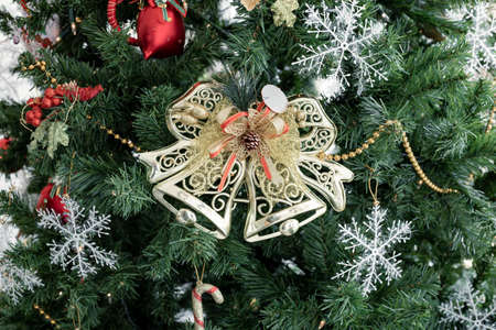 Closeup of golden bell hanging from a decorated Christmas tree with copy space. Christmas and New...