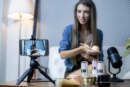 Blogger of caucasian woman with review product and talking camera live recording video on social network at home. Online merchants selling cosmetics on social media via mobile phones.の写真素材