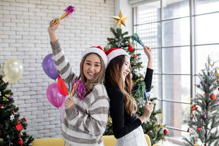 Smiling of Two young Asian women with dance together at home in celebrate Christmas. Celebration of new year at home. Two lovely Thai girls celebrating Christmas and new year.の写真素材