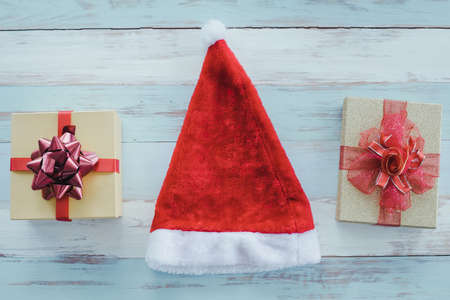 Top view of Christmas composition with red santa claus hat and gift boxes on wooden background and copy space. Accessories of Christmas and new year concept.の写真素材