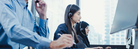 Panorama of group diverse telemarketing customer service staff team in call center. Call center worker accompanied by team. Smiling of customer support operator at work.の写真素材