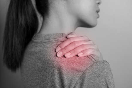 Woman with shoulder pain. Young woman with pain in shoulder. Suffering from pain in shoulder of woman.の写真素材