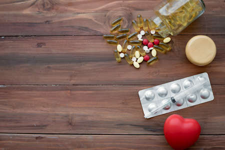 Top view of medicine and heart on wood background with copy space. Concept of medicine in medical. Pills, dietary supplements that are stacked together.の写真素材