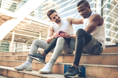 Runner young African American man with Caucasian friend gradually take care after suffering with pain on sports running knee injury. Pain in knee after running of Runner young African American man.の写真素材