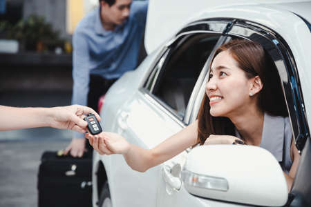 Woman received the keys from the car rental shop after entering into the contract. Car dealer giving...