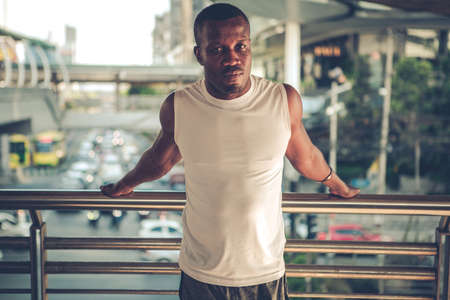 Fit runner African American young man doing stretching in the city. Handsome young man exercise...