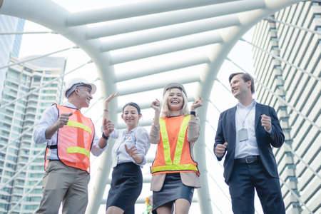 Successful group of businessmen and engineers with cheerful at outdoor in the city. Doing business together of a group of engineers and business people. Two engineers and two business people.の写真素材