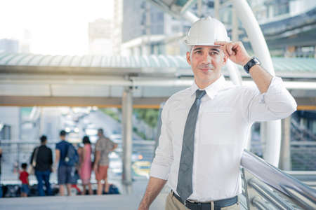 Confident construction engineer in hard hat looking at construction projects. Senior engineer with...