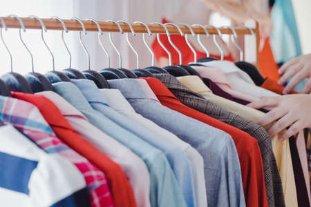 Customers who are choosing shirts on clothesline. Variety and modern fashion clothes, orderly hanging on the clothesline. Clothes hang on shelf in a designer clothes store. Fashion trend concept.の写真素材