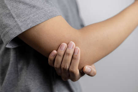 Women with pain in elbow. Acute pain in a elbow. Young woman holds on to elbow.の写真素材