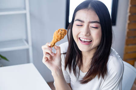 Face of young woman was happy to eat the delicious fried chicken. fried chicken drumstickの写真素材
