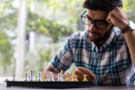 Man developing chess strategy, playing board game. Man thinking chess figure with team strategy and leadership concept. Clasped hands planning strategy with chess figures on table.の写真素材