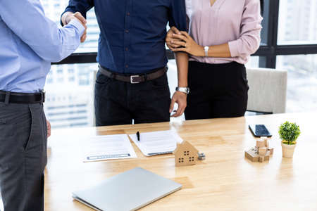 Concept buy or sell home, couple shaking hands as successful agreement in transaction contract of house with broker.の写真素材