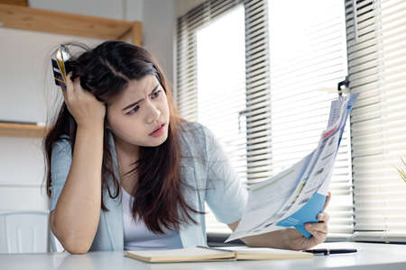 Young woman stressed over credit card debt collection documents. Financial problem concept.