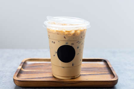 Iced latte coffee on wooden tray with black logo sticker.の写真素材