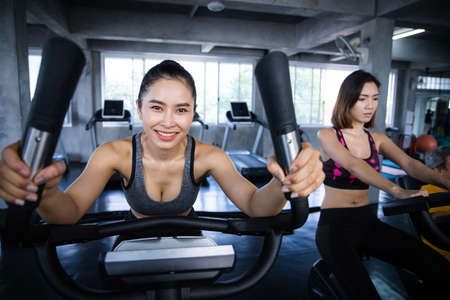 Young woman doing cardio exercises in spinning class with exercise machines in gym.