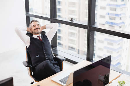Relaxed man take break from work put hands behind head lean on comfy chair in the office.の写真素材
