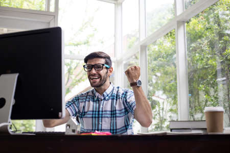 Success of young Caucasian man working from home by computer in work at home concept.の写真素材