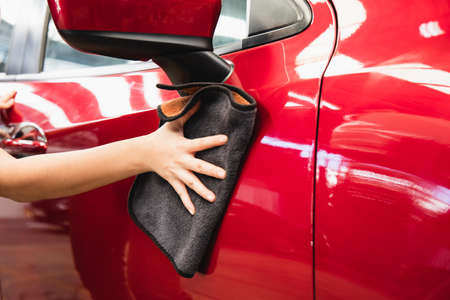 Woman dry wiping car surface with microfiber cloth after washing.の写真素材