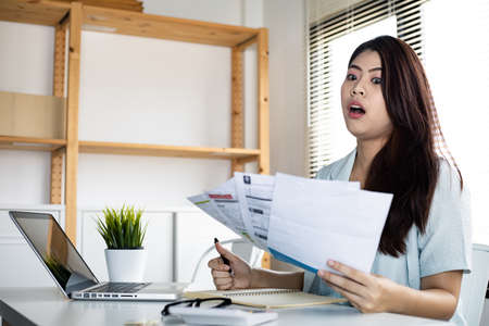 Young woman shocked and stressed over credit card debt collection documents. Financial problem...