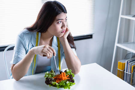 Asian women intend to lose weight but tired of eating vegetable saladeating healthy food was difficult for her.の写真素材