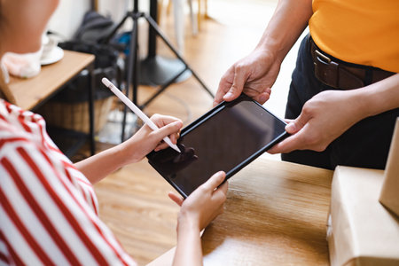 Young woman signs on tablet to receive parcel from express delivery at the home.