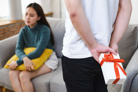 Young man surprise girlfriends with a gift box held on the occasion of the anniversary of love.