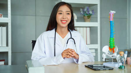 Female orthopedic doctor explaining how to maintain a healthy body through a video. Female doctor records a video in a doctor's office in a hospital.の写真素材