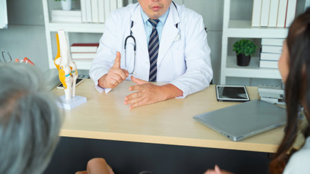 Daughter took an elderly woman patient to the doctor to follow up with knee treatment at the hospital. Male doctor giving advice and tell the patient about the precautions in knee treatment.の写真素材