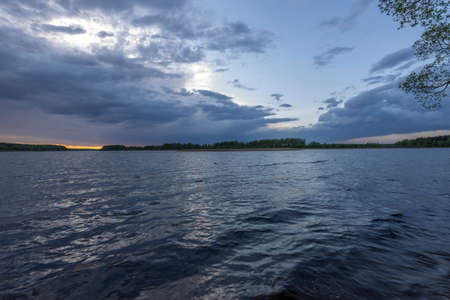 Evening landscape with a river and clouds. Dramatic sunset over the river.の写真素材